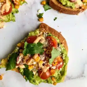avocado toast with tomatoes, corn, cotija cheese, cilantro, and chipotle aioli.