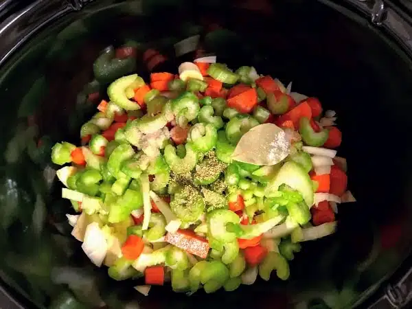 chopped celery, onions, carrots, and parsnips with seasonings in a slow cooker