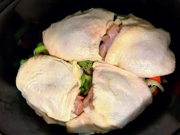 chicken thighs on top of celery, onions, and carrots