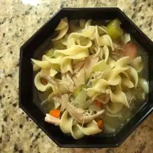 slow cooker chicken noodle soup in a black bowl.