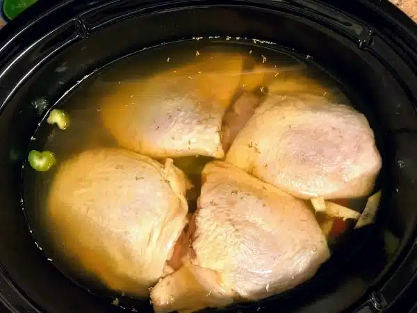chicken thighs, broth and vegetables in slow cooker