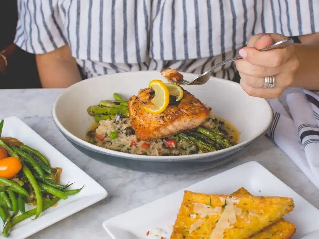 intuitive eating vs. mindful eating, women eating salmon, asparagus, and rice