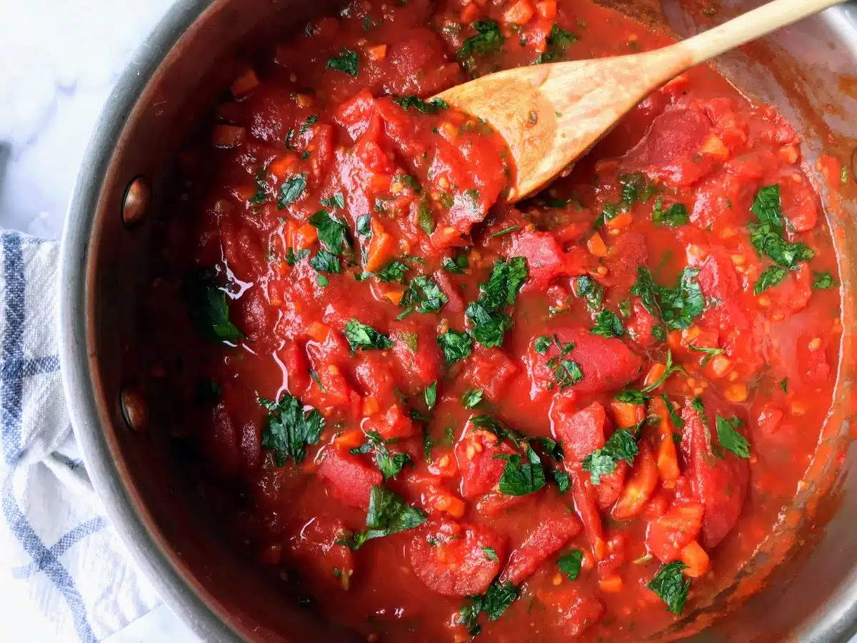 Low FODMAP pasta sauce in a skillet with a wooden spoon.