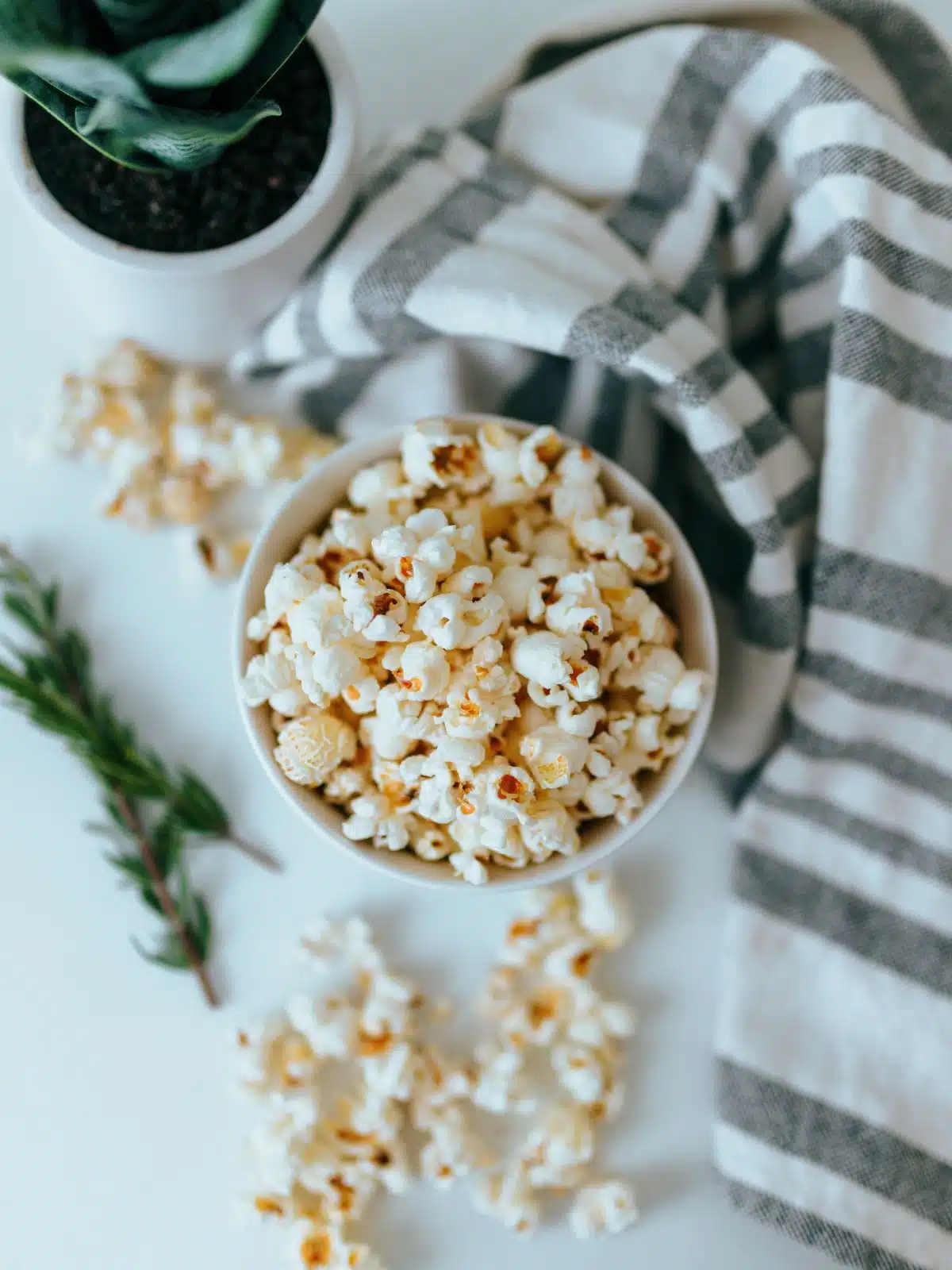 popcorn in a bowl with rosemary sprigs on the side. 