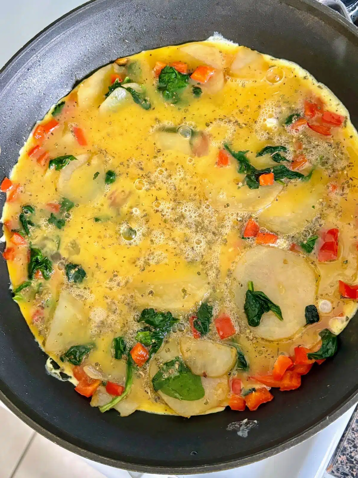 Eggs, potatoes and vegetables cooking a skillet.