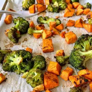 Roasted sweet potatoes and broccoli on a baking sheet.