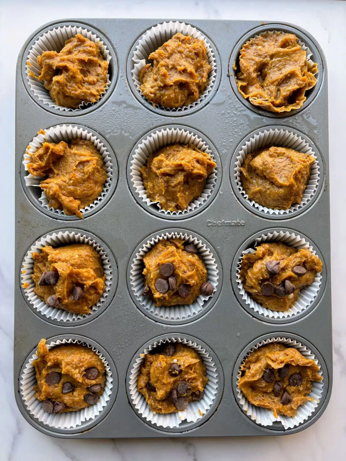pumpkin muffin batter added to lined muffin tin.