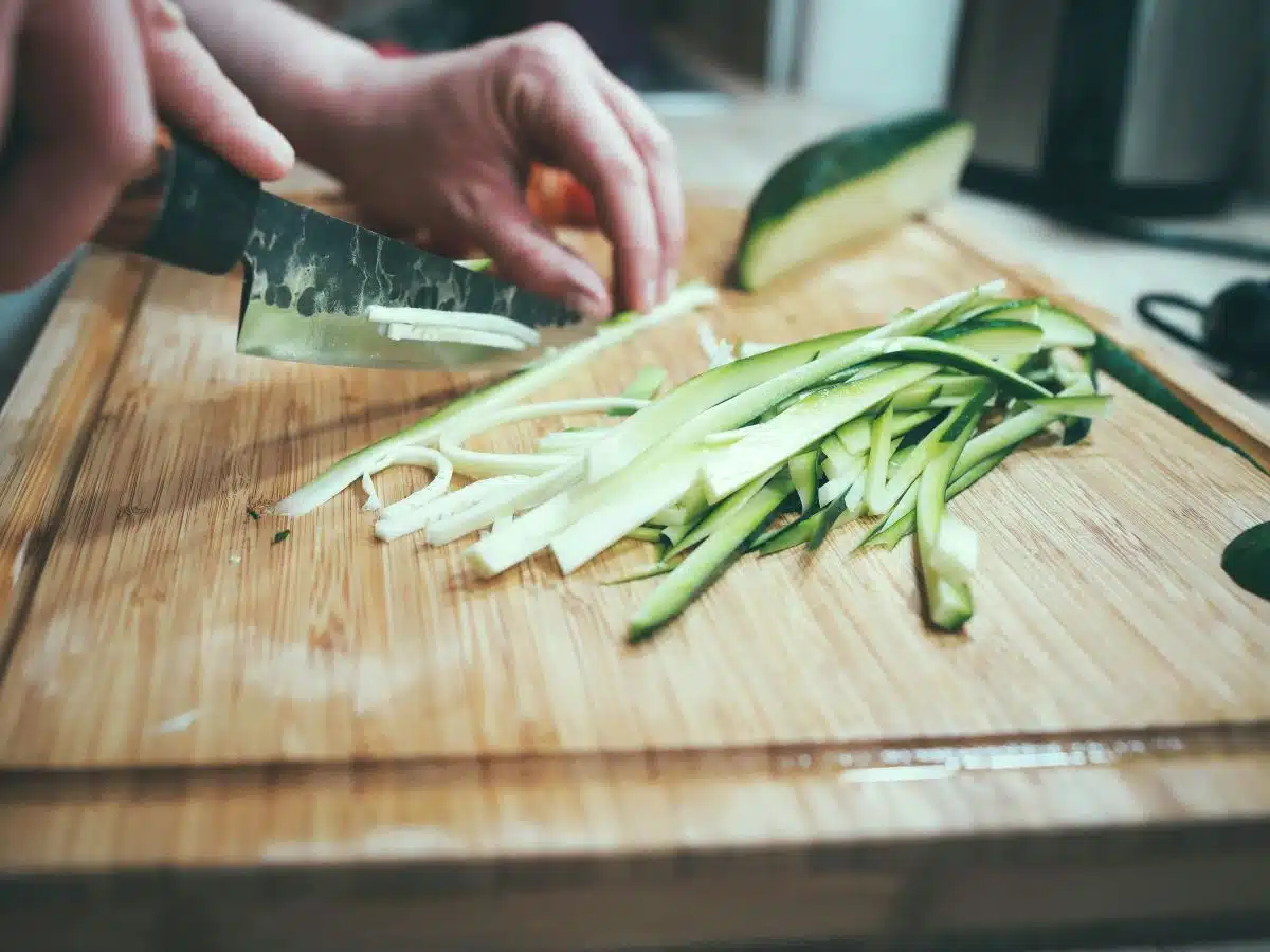 A person slicing zucchini into thin strips.